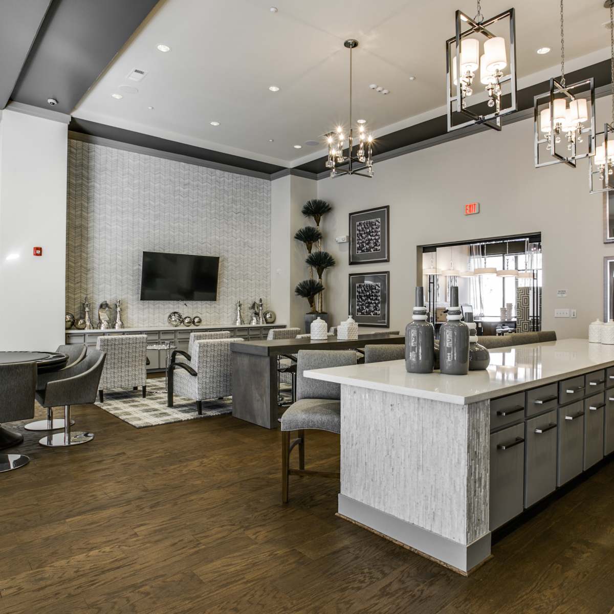 A modern kitchen and dining area features gray cabinetry, a large island with bar seating, and stylish lighting.