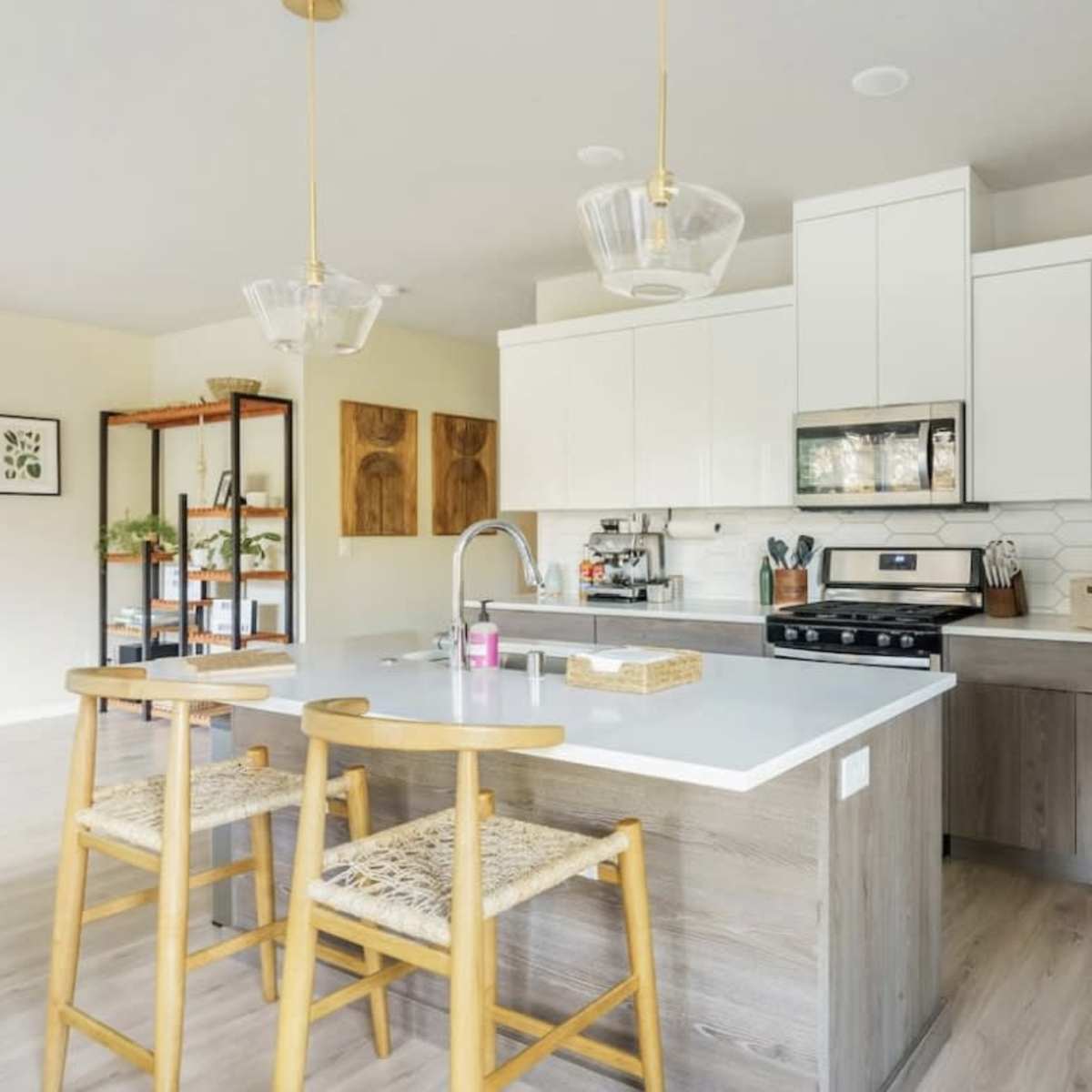 A modern kitchen features white cabinetry, a gray countertop, and wooden barstools, providing a clean and functional space.