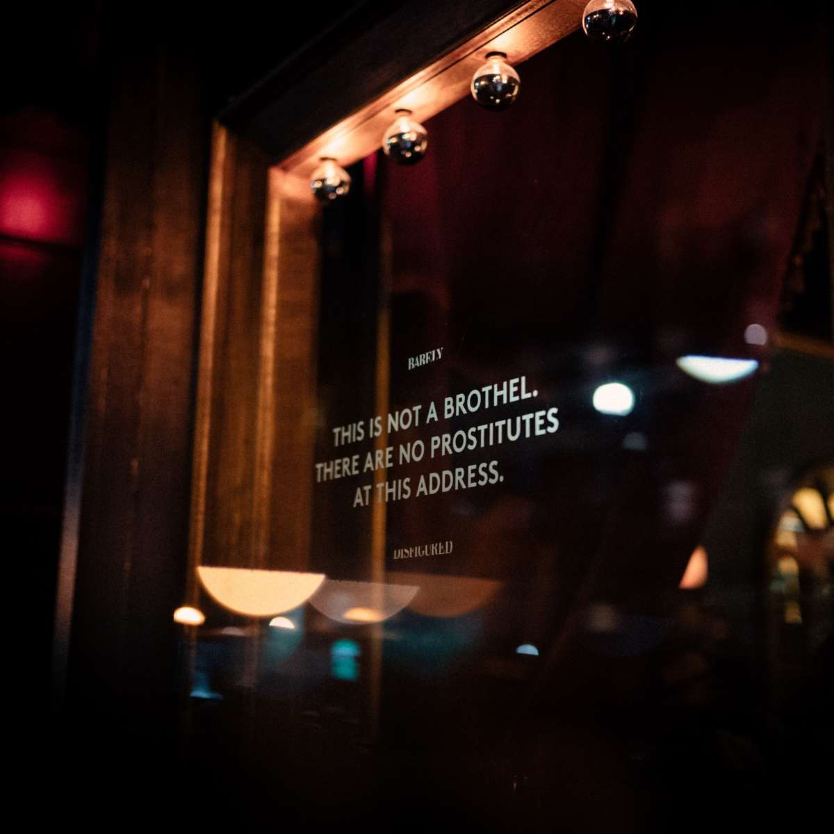 A sign in a window states, "THIS IS NOT A BROTHEL. THERE ARE NO PROSTITUTES AT THIS ADDRESS."
