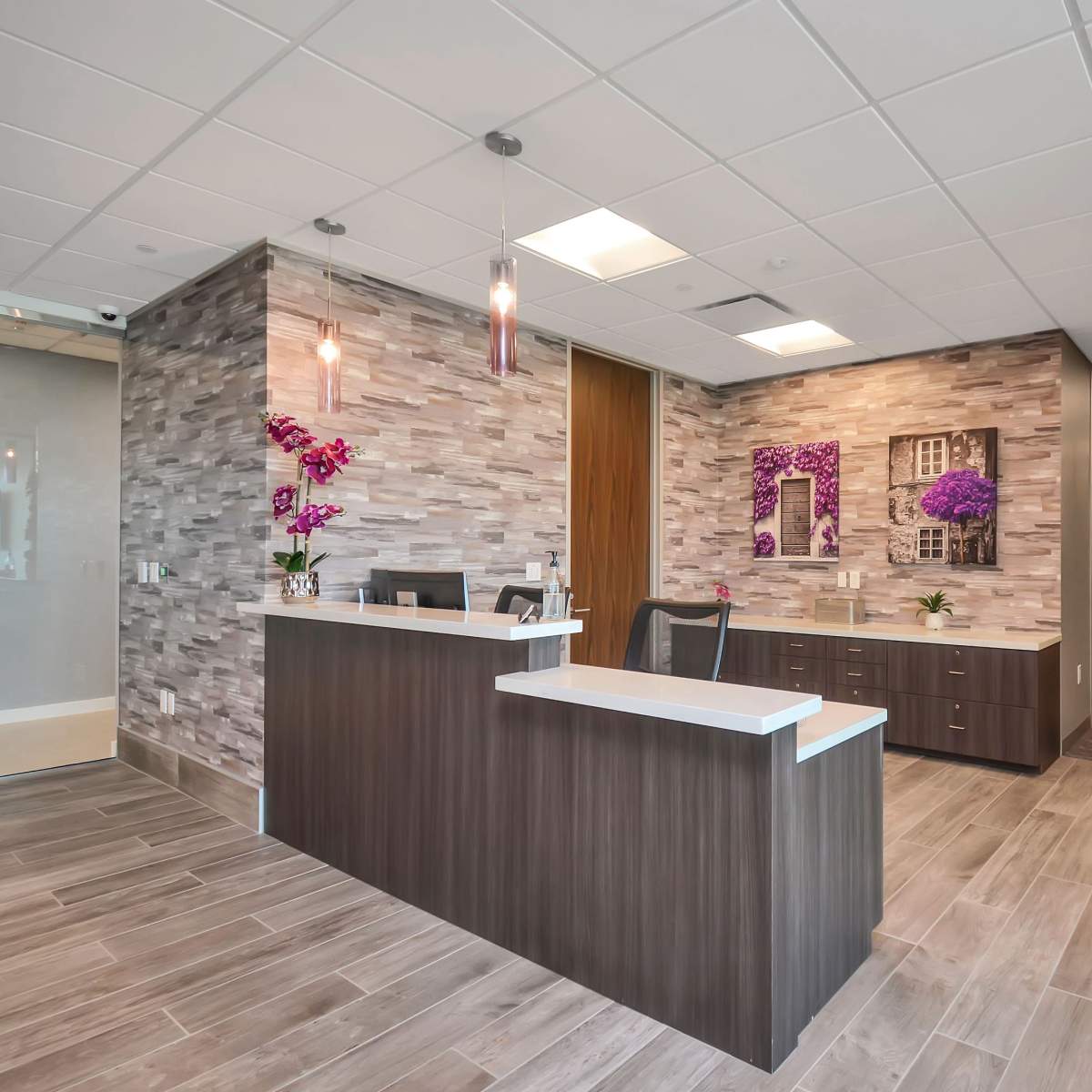 A modern reception area with a desk, decorative wall features, and a hallway leading to other rooms.