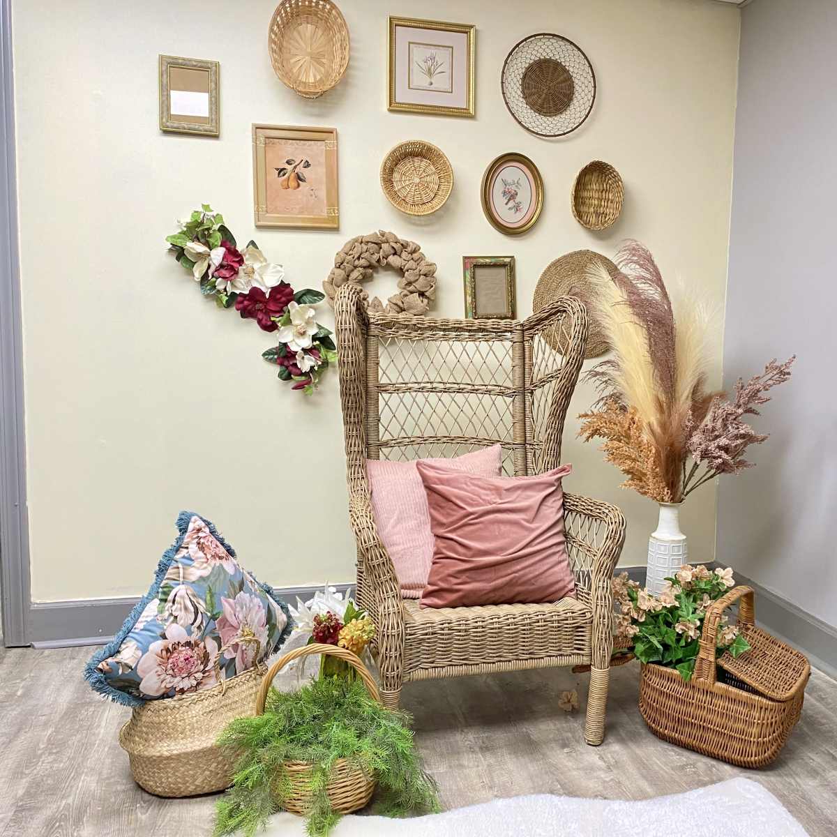 A decorative corner featuring a wicker chair surrounded by various wall art, floral arrangements, and woven baskets.