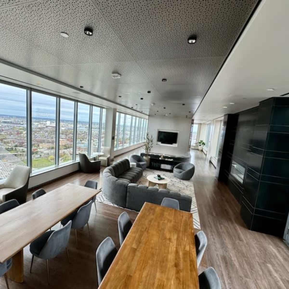 A modern, open-plan living space features large windows with city views, a dining table, and a comfortable seating area.