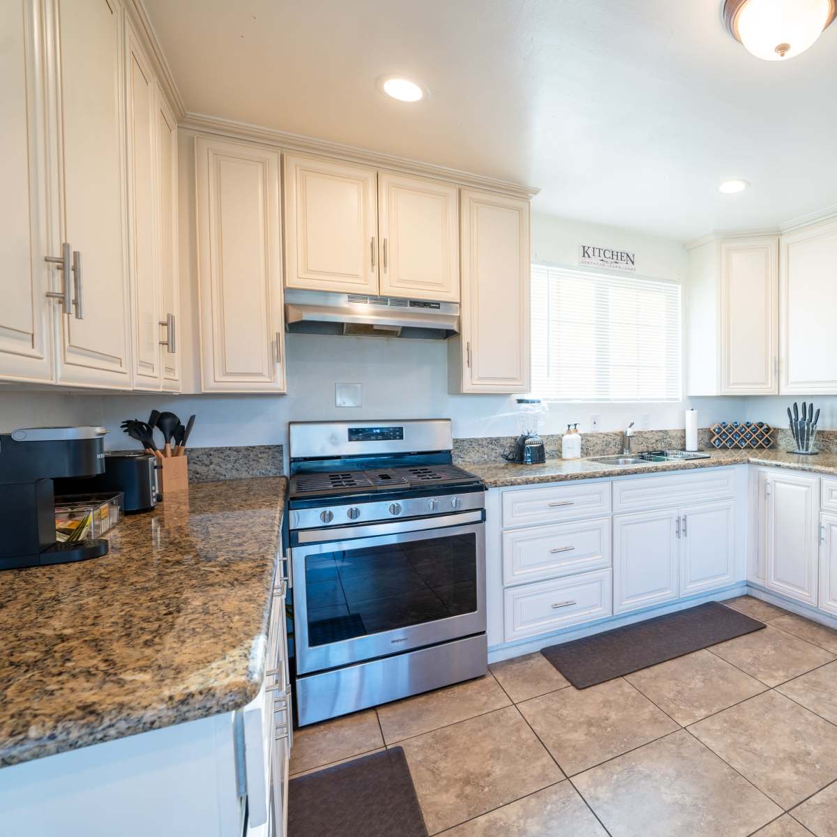 A modern kitchen with white cabinets, a stainless steel refrigerator, and granite countertops.