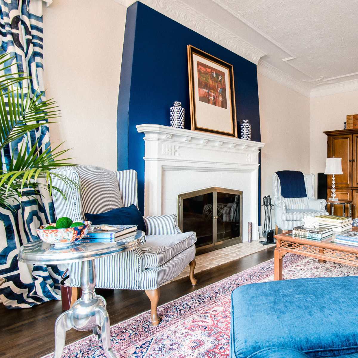 A living room featuring a blue accent wall, a white fireplace, and a mix of comfortable seating arrangements.