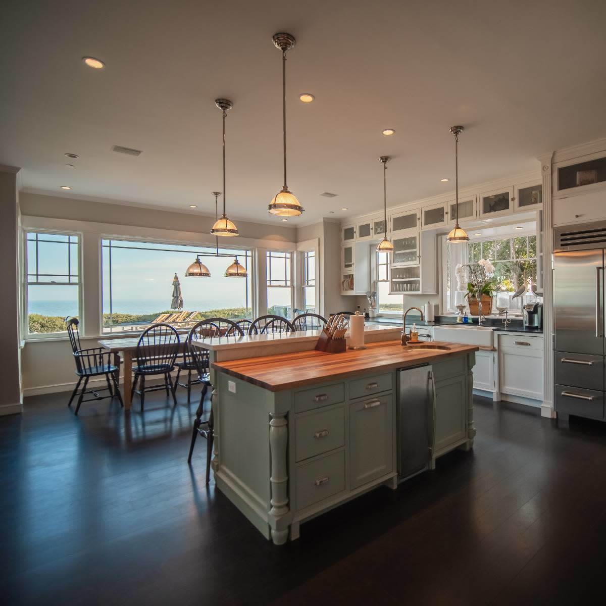 A spacious kitchen with a central island, modern appliances, and a dining area that overlooks a scenic view.