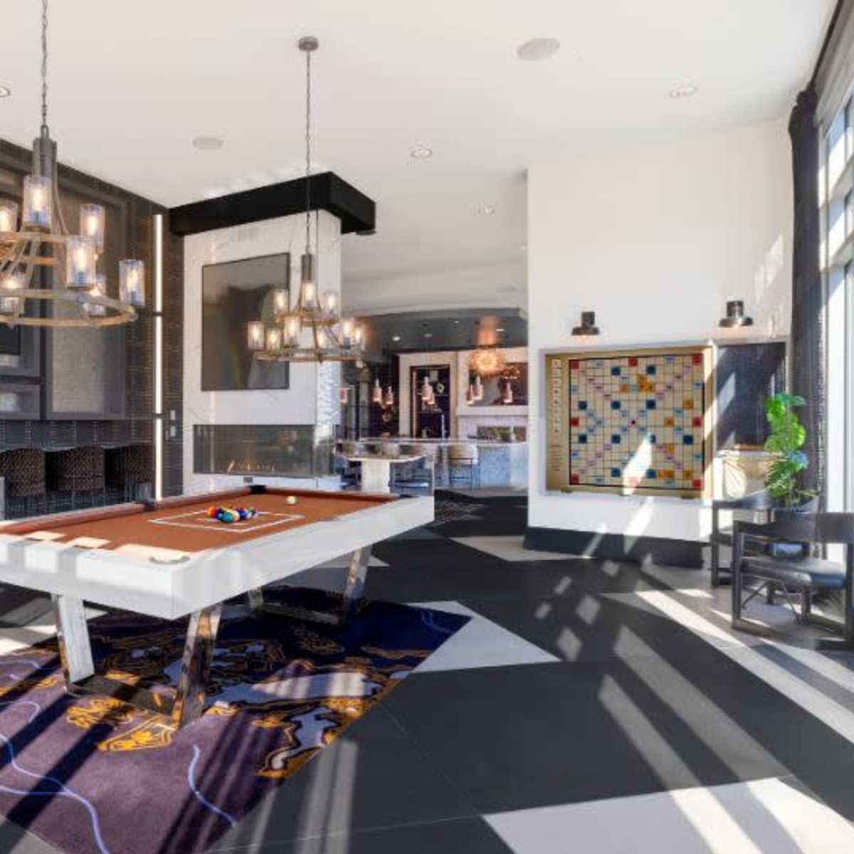 A modern recreational room featuring a billiard table, stylish lighting fixtures, and a patterned rug on a black and white tiled floor.