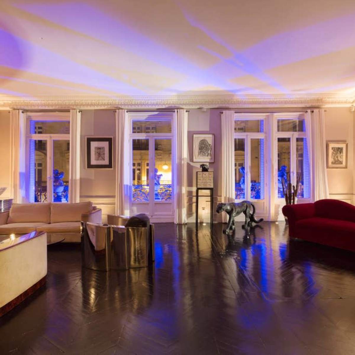 A spacious room with elegant furnishings, large windows allowing natural light, and a mix of modern and classic decor.