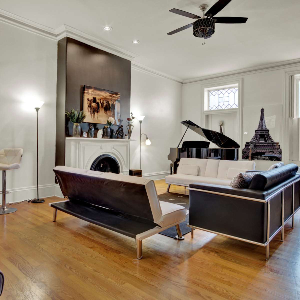 The living room features a black and white color scheme, a grand piano, an Eiffel Tower replica, and modern furniture arranged around a fireplace.
