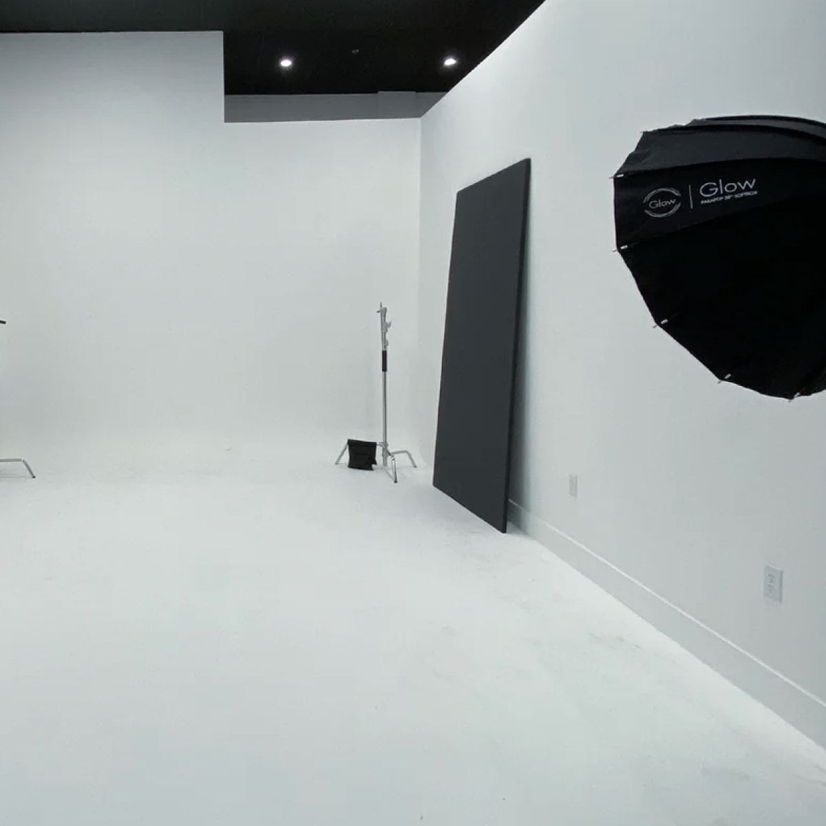 A spacious photography studio with white walls and two lighting setups on either side.