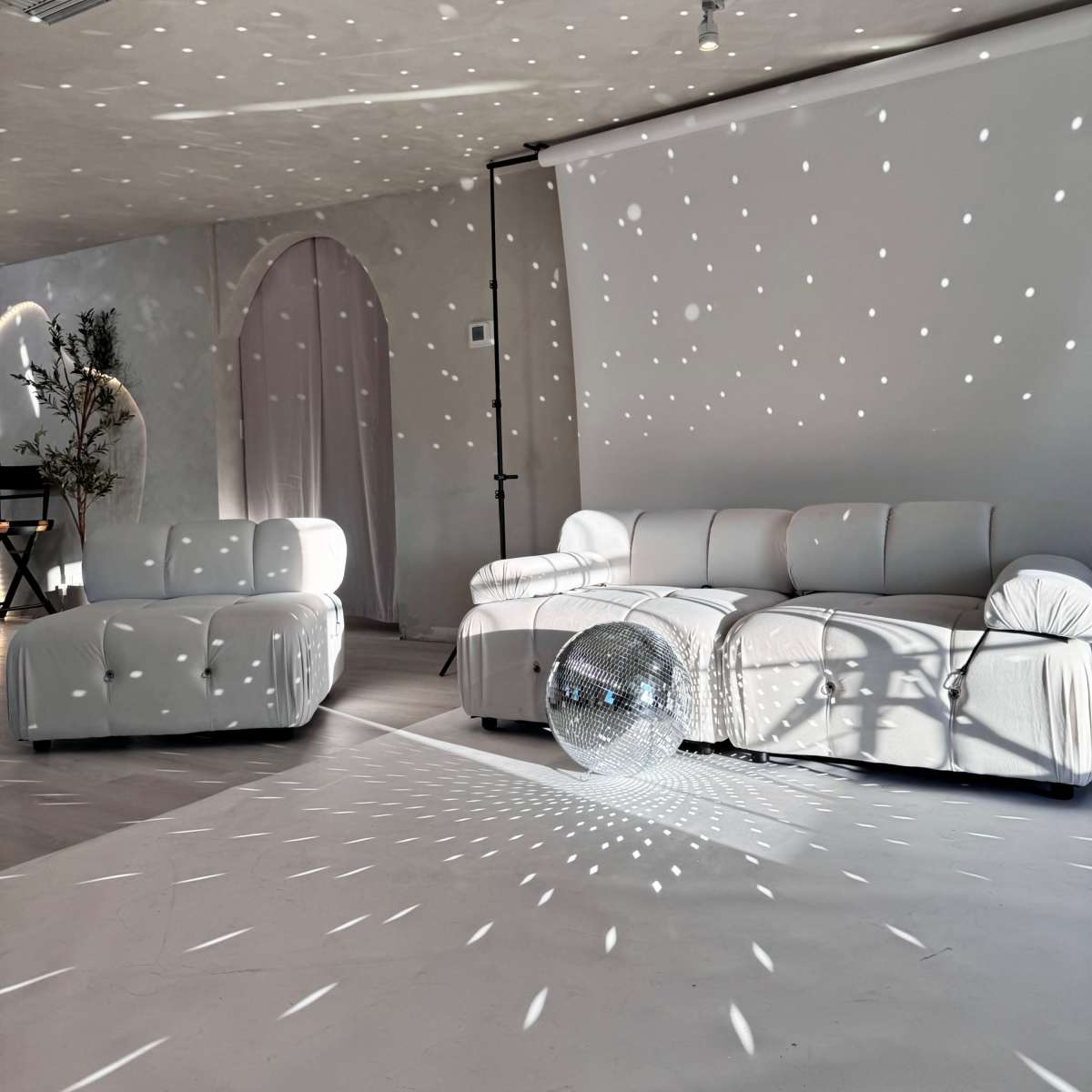 The room features white sofas and a disco ball casting light patterns on the walls and floor.