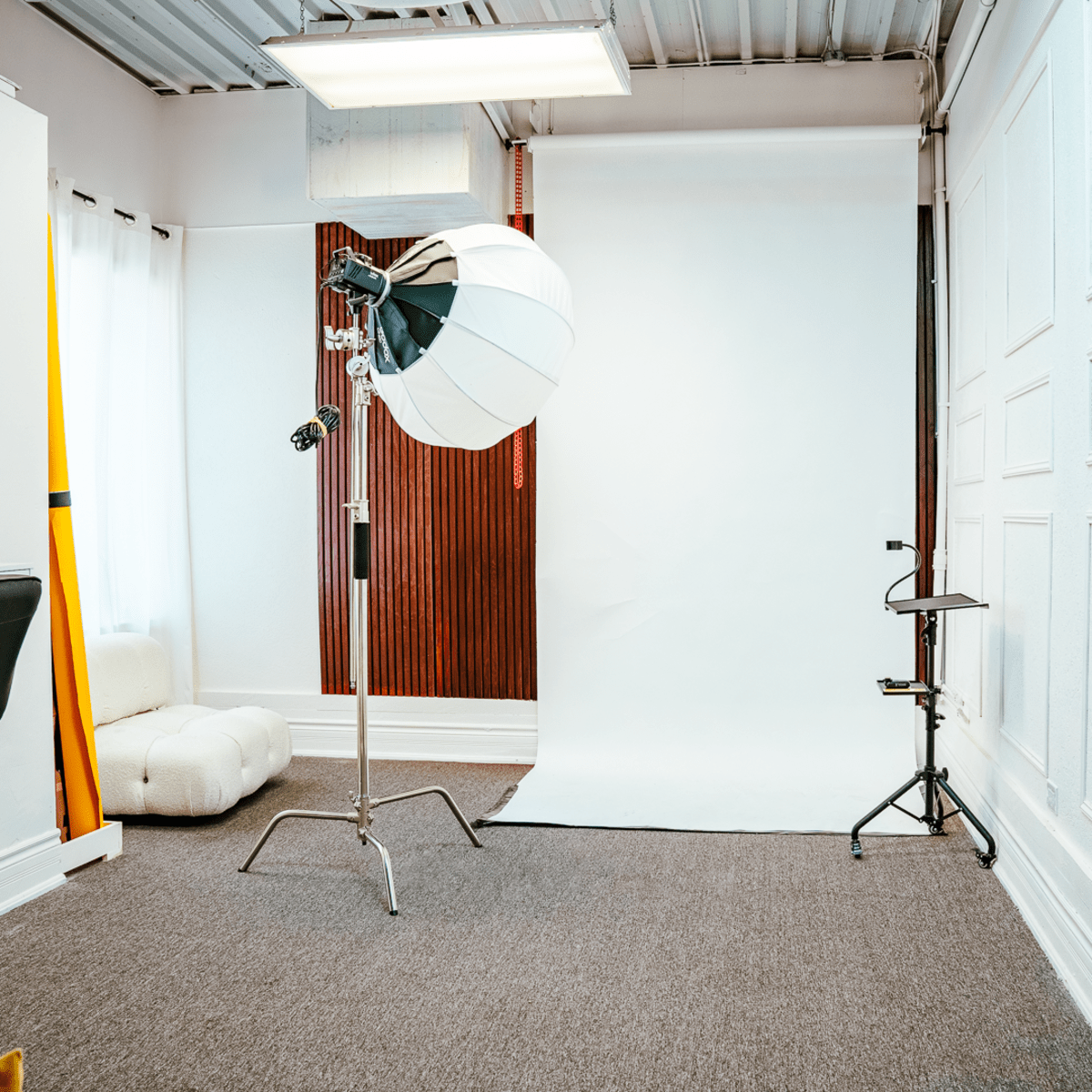 A photography studio with a backdrop, a light stand, and a chair.