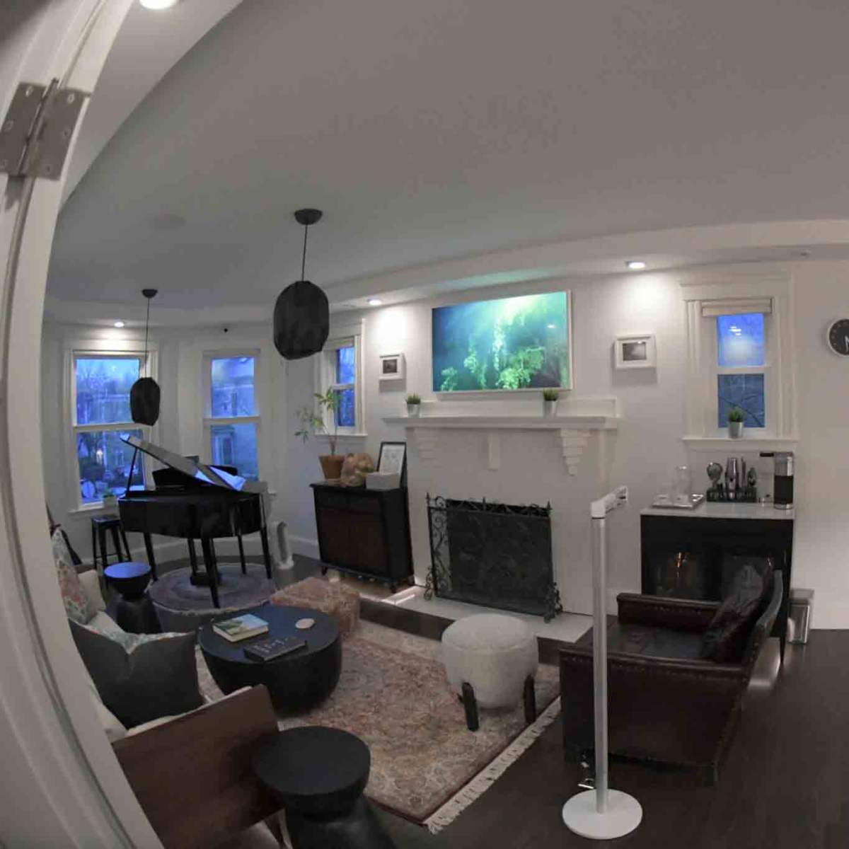 A spacious living room featuring a piano, a fireplace, and an aquarium mounted on the wall, with a mix of modern and traditional furnishings.