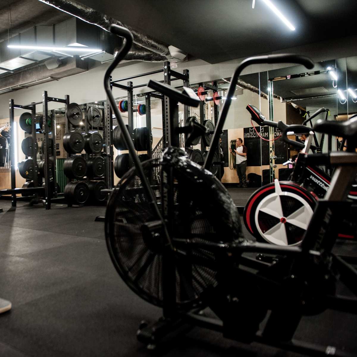 A modern gym interior with various exercise equipment, including stationary bikes and weightlifting machines.