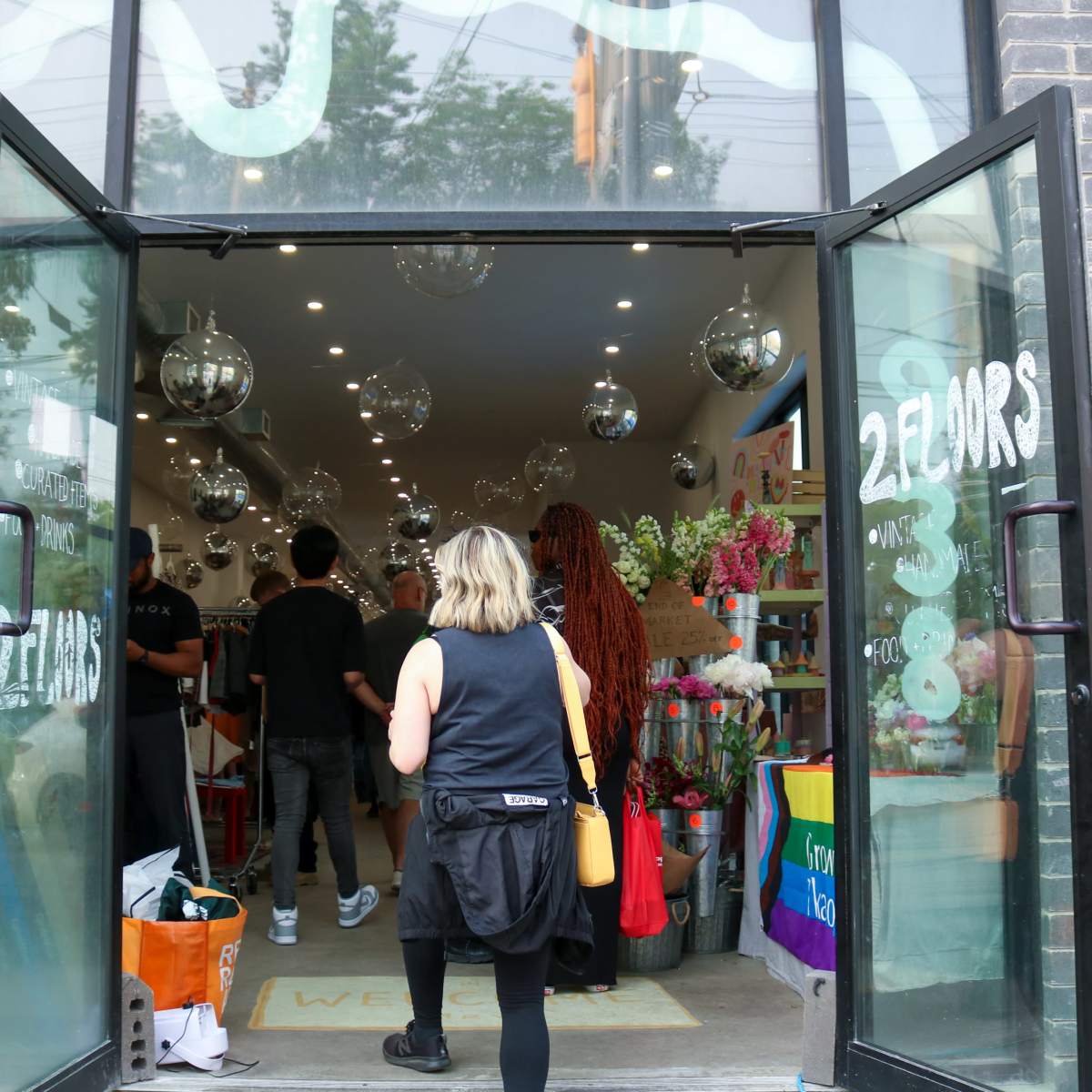 A woman enters a brightly lit shop with decorative items and colorful displays while several people browse inside.