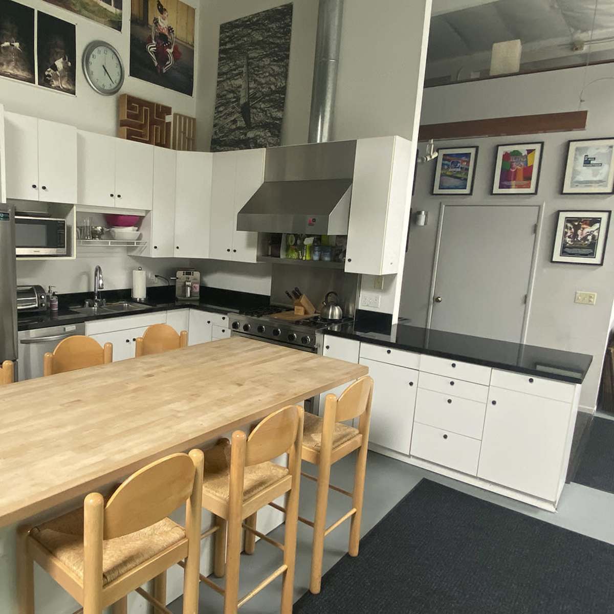 A spacious kitchen features a wooden table with six chairs, stainless steel appliances, and a black countertop.