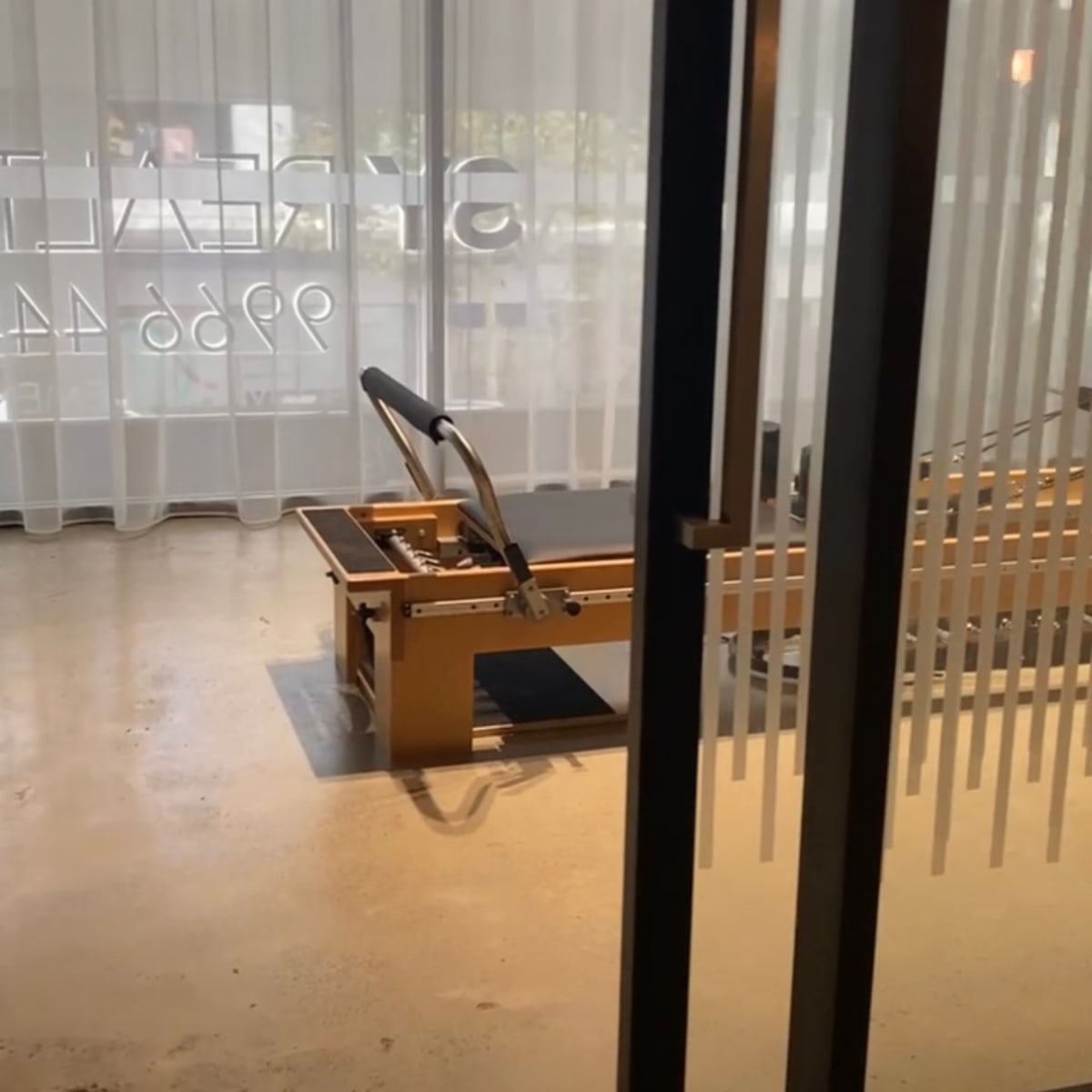 A reformer machine for Pilates set up in a well-lit studio with large windows.