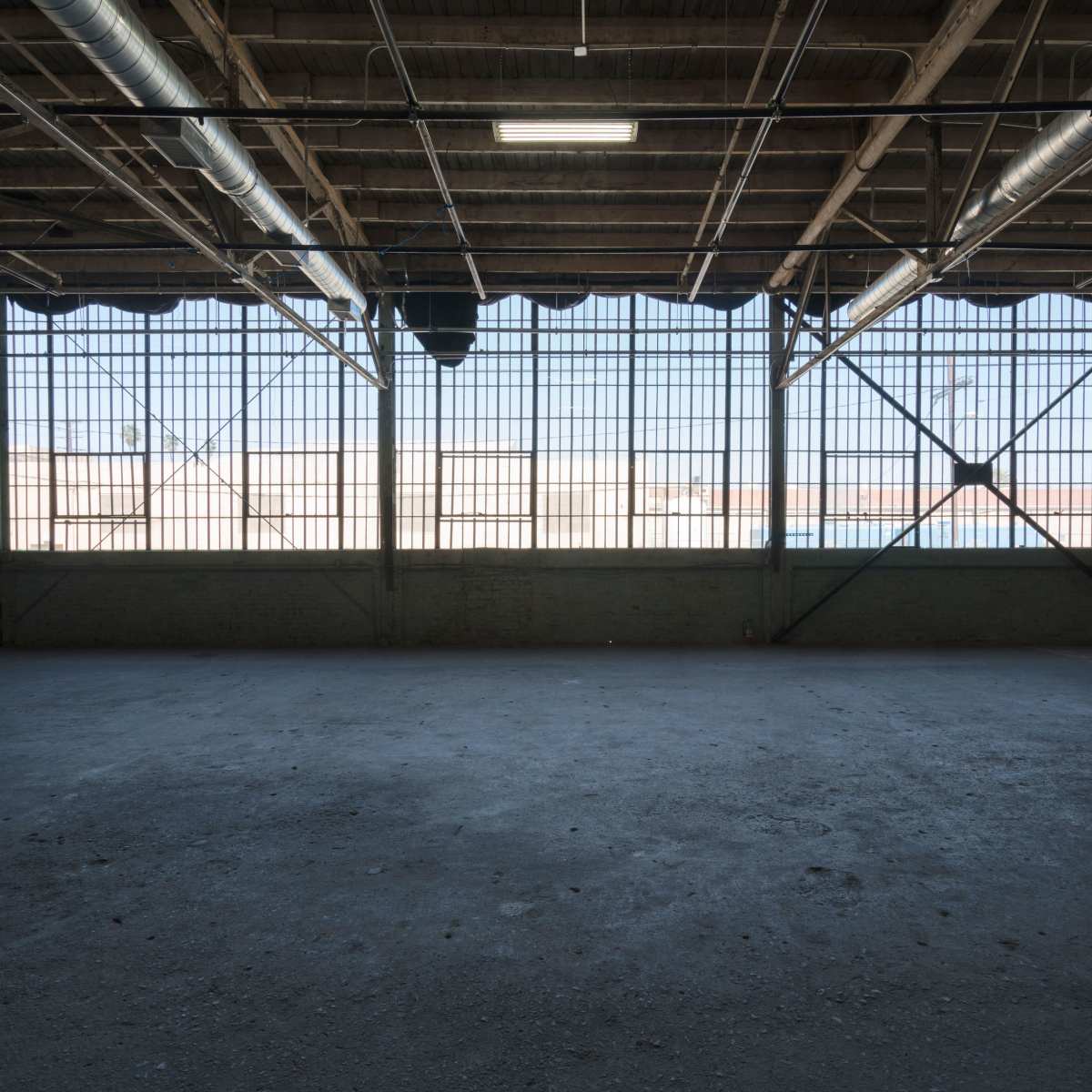 An empty industrial space with large windows allowing natural light to enter.