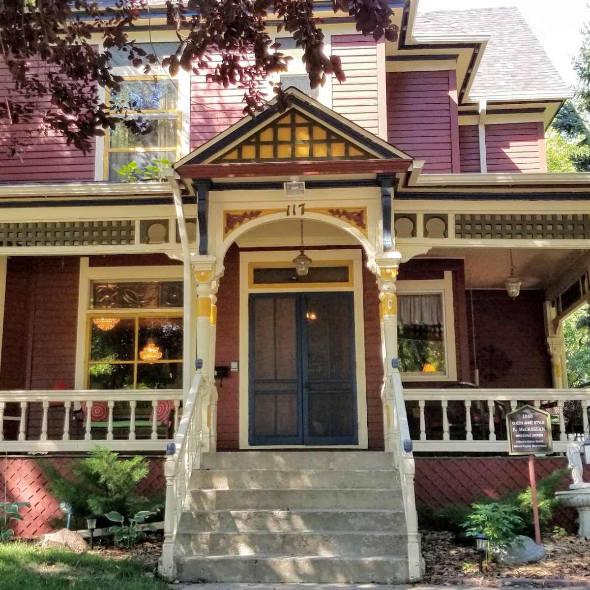 A two-story Victorian-style house with a wraparound porch and a central front door.