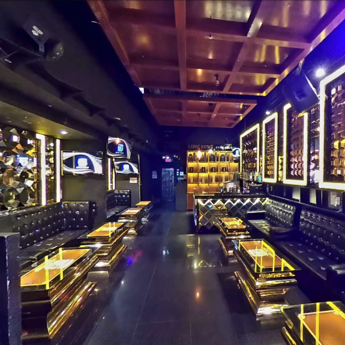 A stylish, modern lounge with gold accents, black seating, and illuminated walls featuring decorative mirrors.