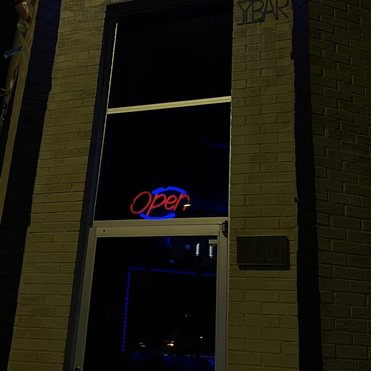 The exterior of Lux Lounge DC features a brightly lit "Open" sign in the window against a brick wall.