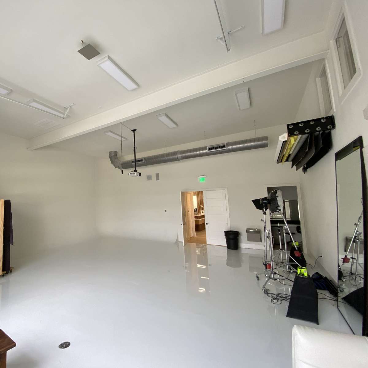A large, empty studio space featuring a high ceiling, white walls, and a polished floor.