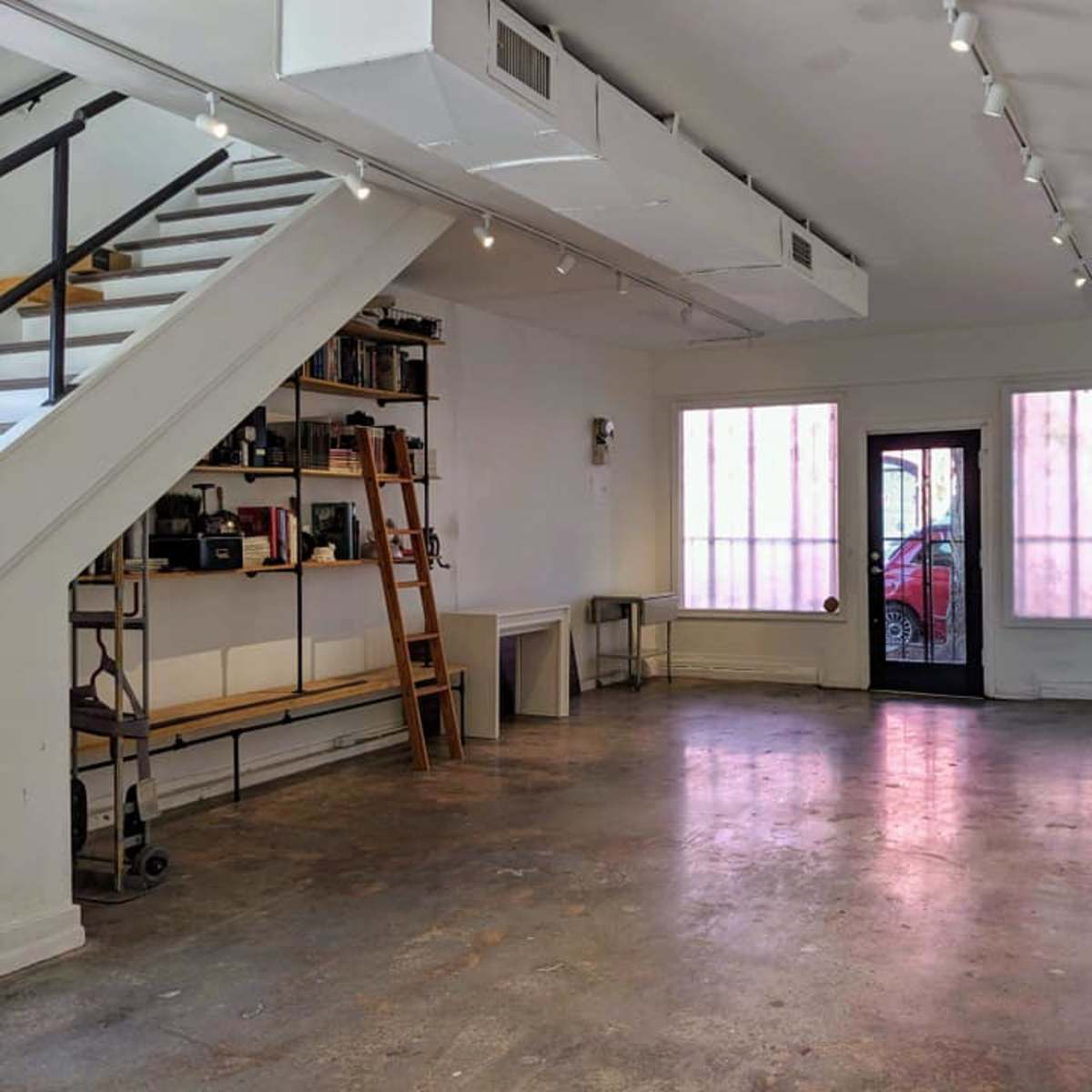 A spacious, empty room with a staircase on the left and large windows in the front.