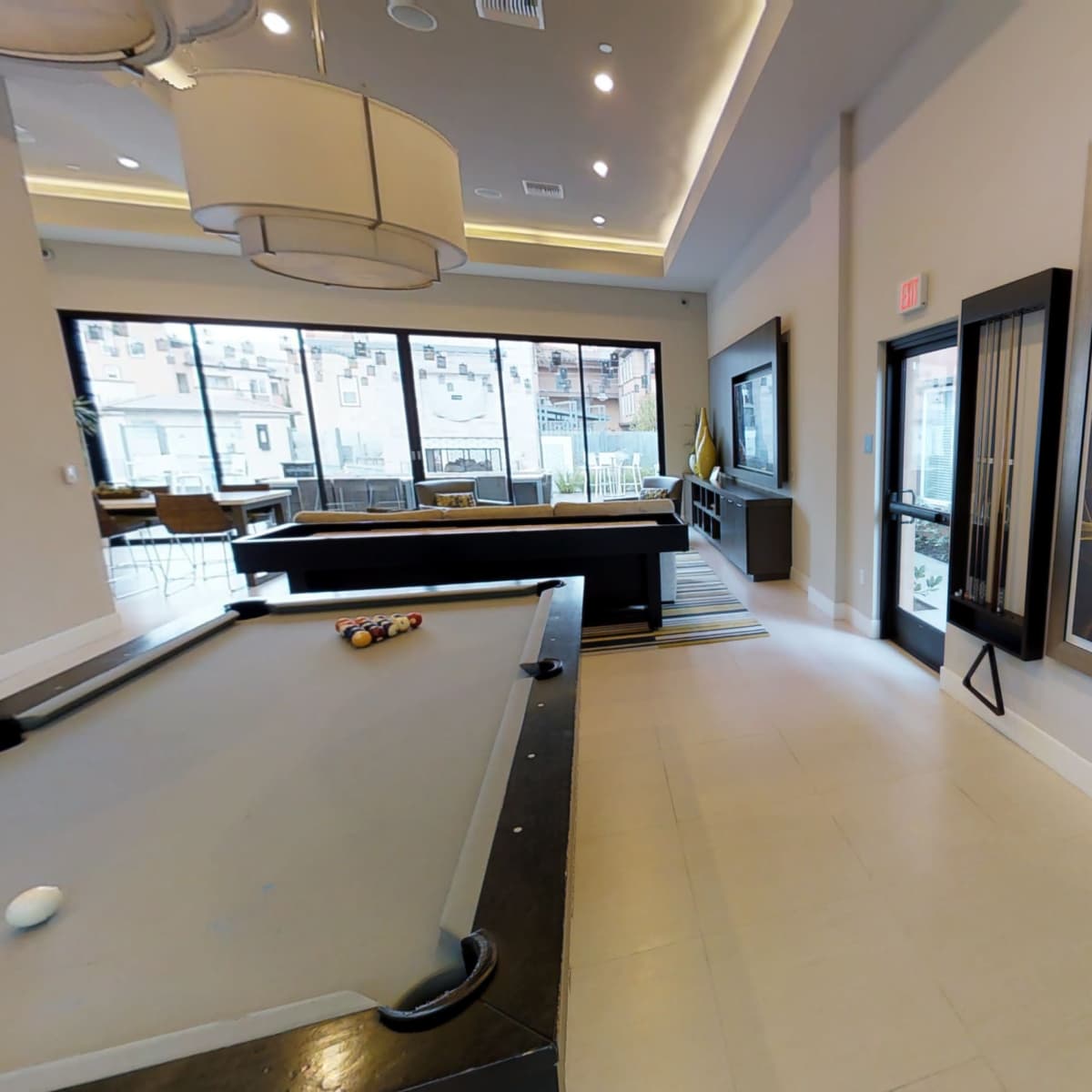 A modern lounge area featuring a pool table, a large abstract painting, and floor-to-ceiling windows.