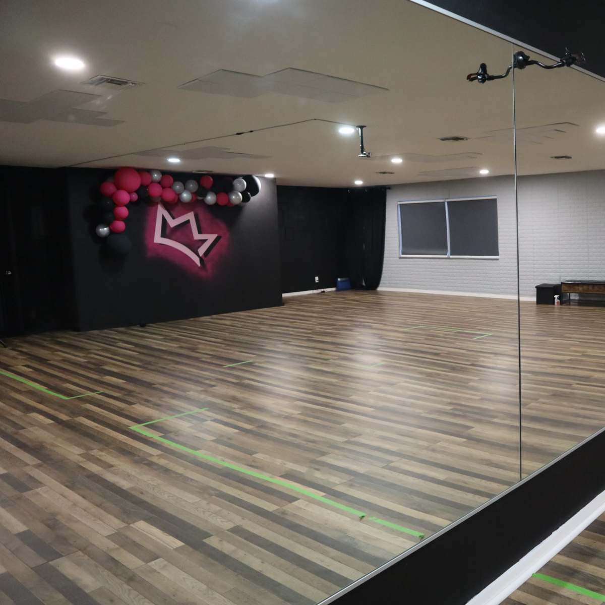 A dance studio featuring a mirrored wall, hardwood floors, and a balloon decoration in the corner.