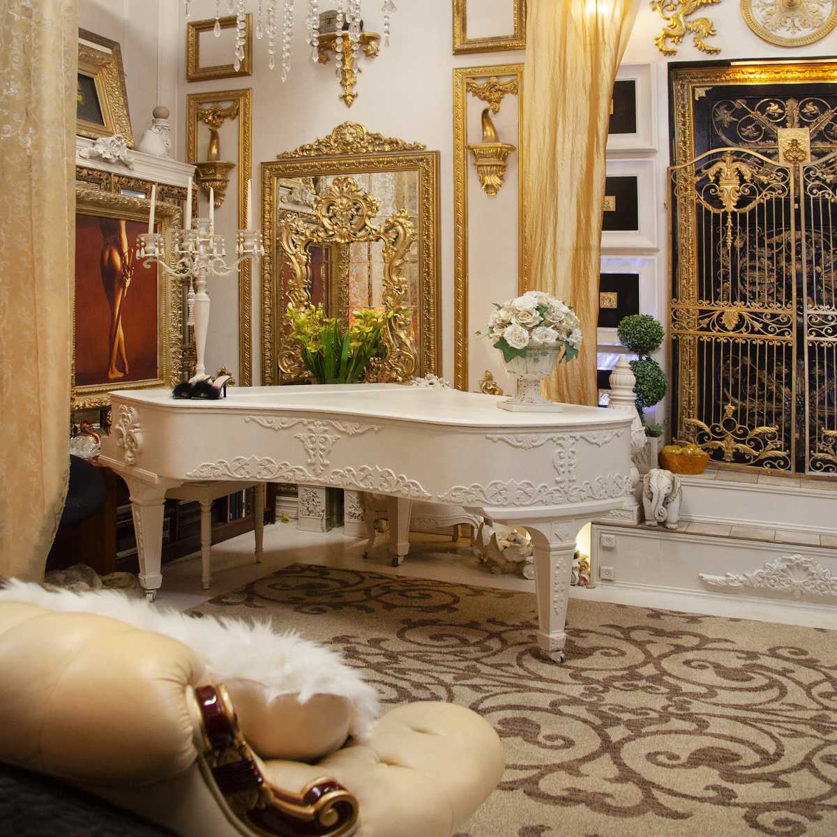 An elegantly decorated room featuring a white grand piano, ornate mirrors, and gold accents throughout the decor.