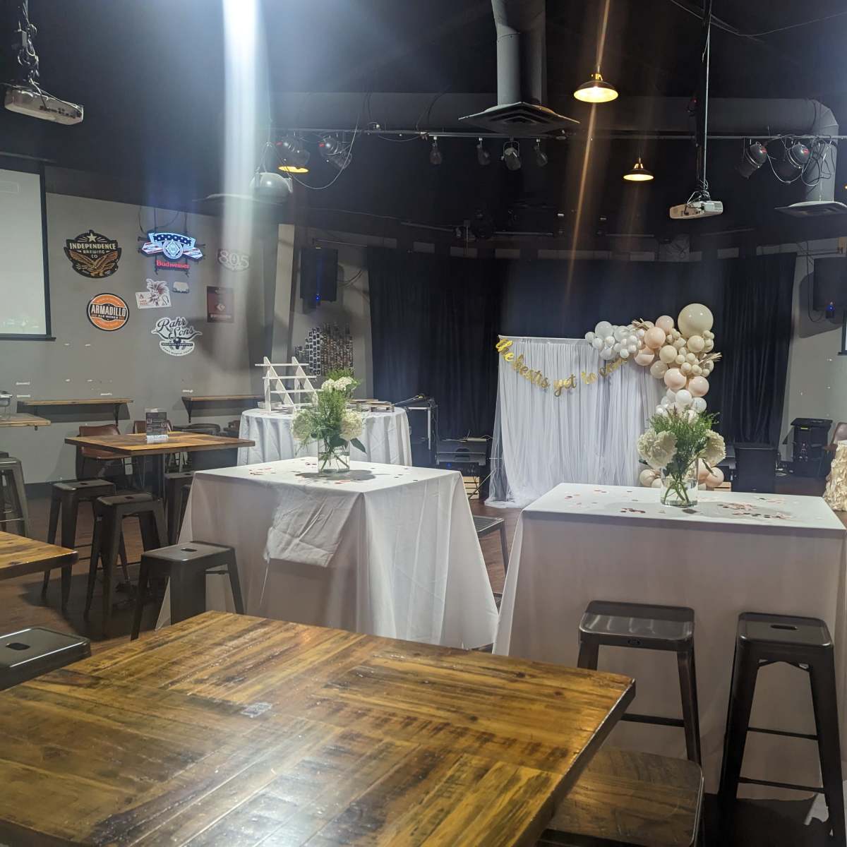 A decorated event space with tables set for a celebration, featuring a backdrop of balloons and floral arrangements.