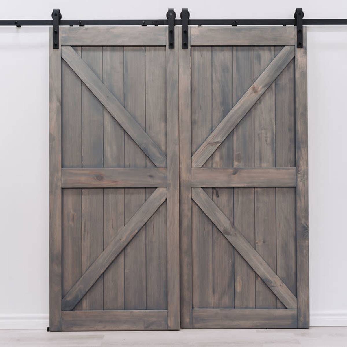 A pair of wooden barn doors mounted on a black metal track against a white wall.