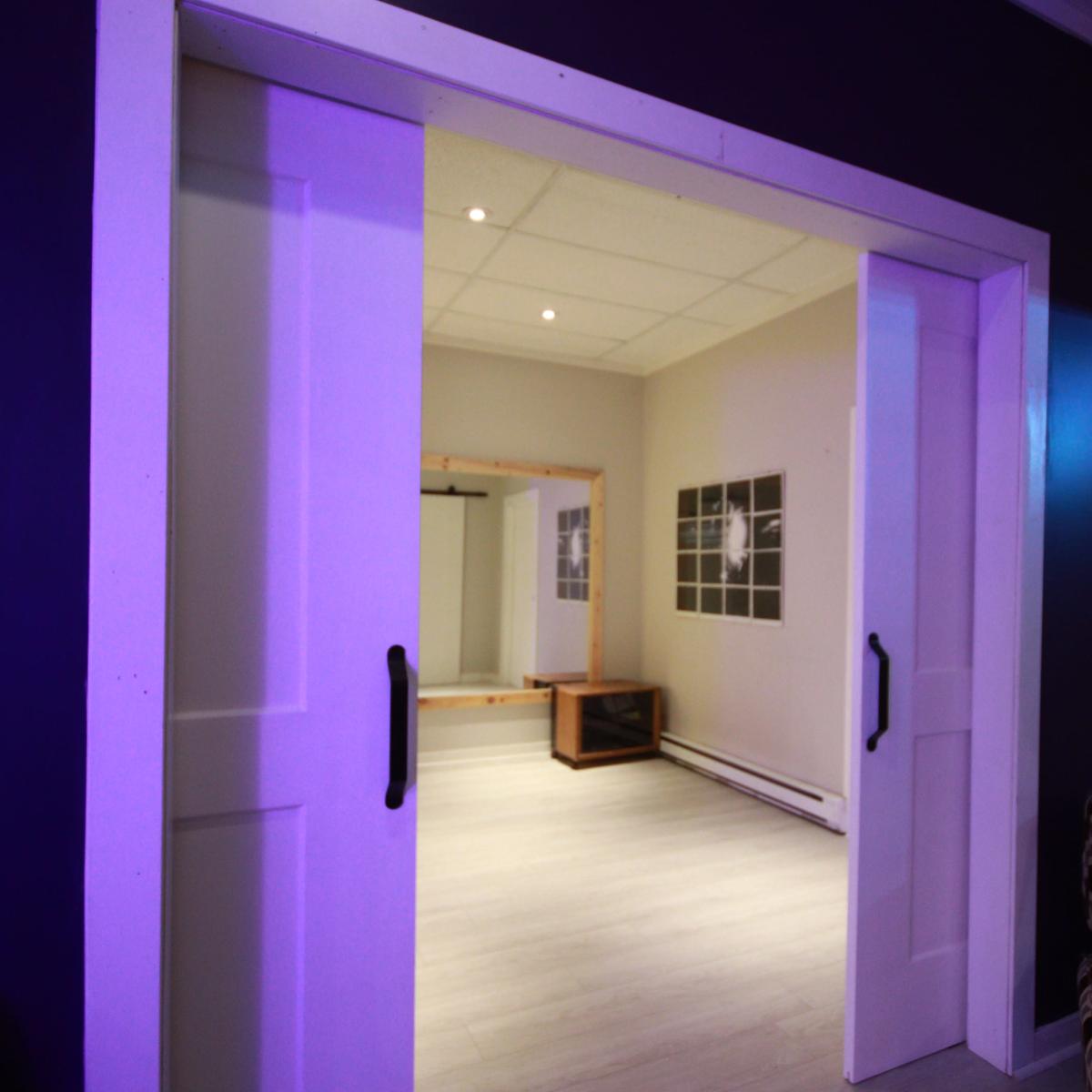 A partially open sliding door leading into a brightly lit room with minimalist decor and light-colored flooring.