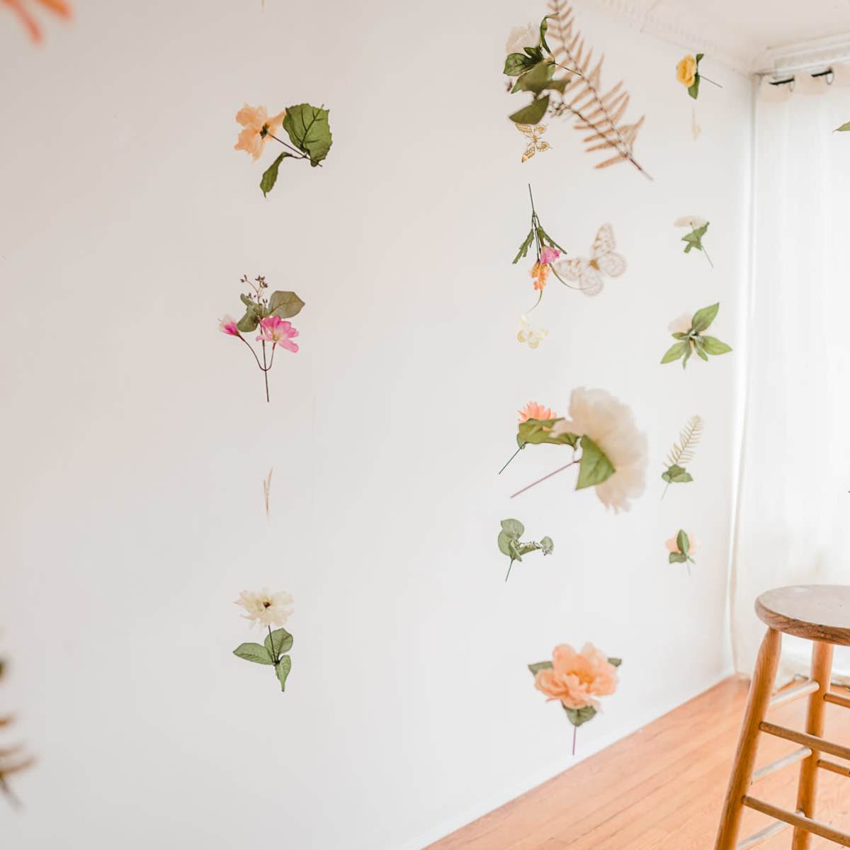 A stool stands on a wooden floor in a room with flower and butterfly decorations hanging from the walls.