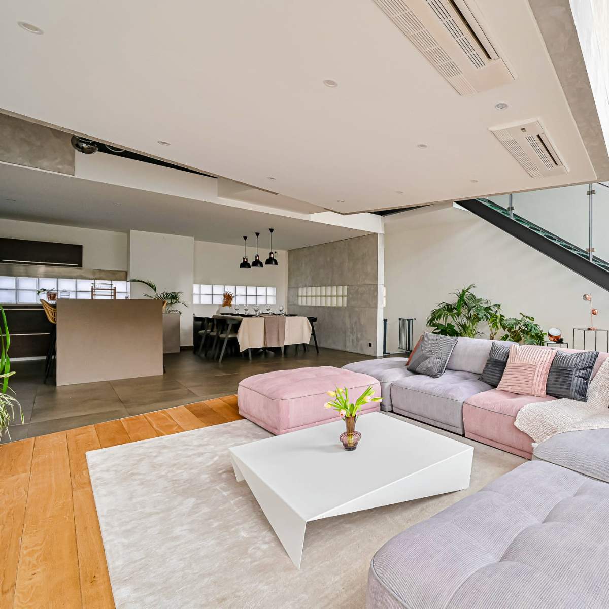 A modern living room with a large sectional sofa, a coffee table, and a staircase leading to an upper level.