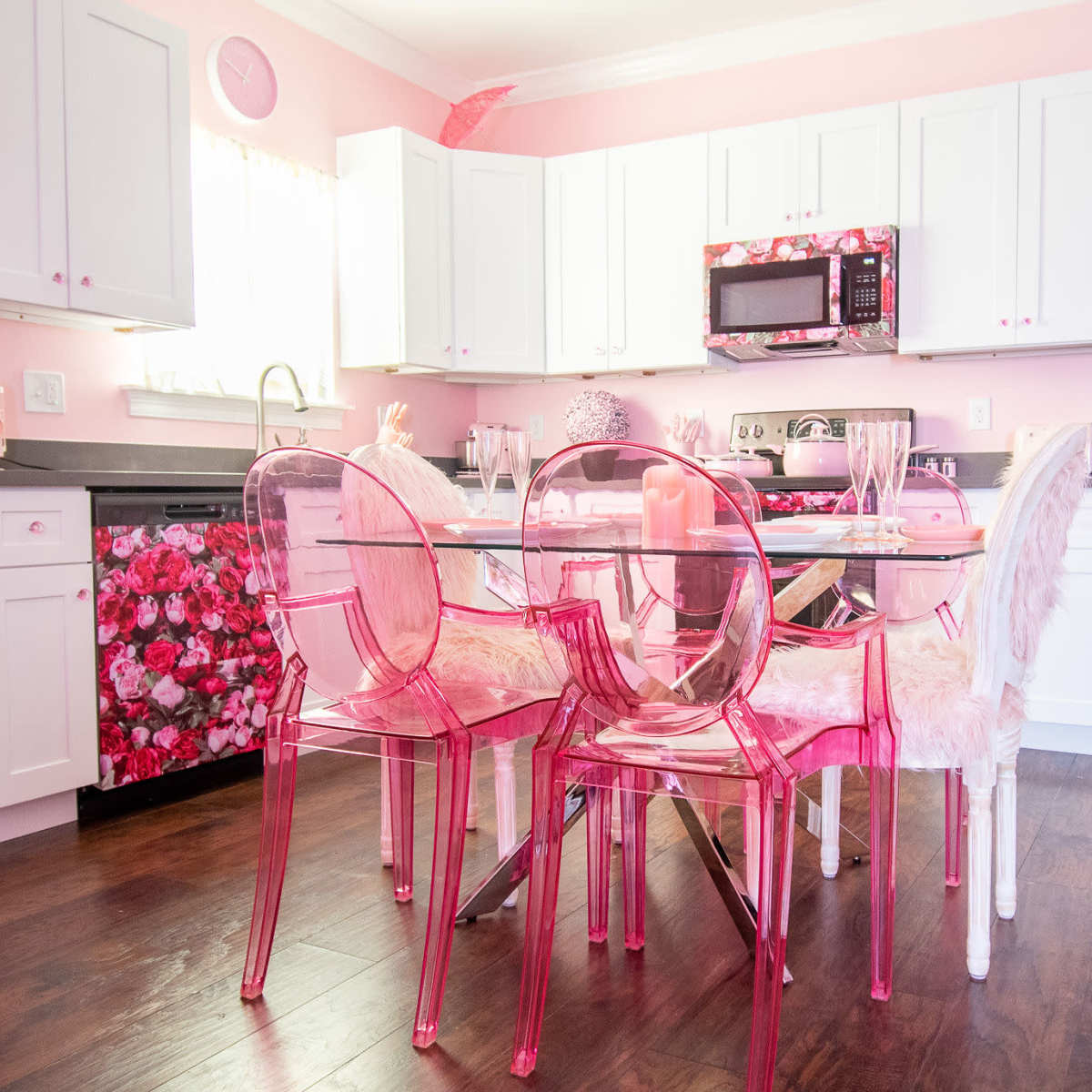 The kitchen features white cabinets and floral-patterned appliances, with a glass dining table surrounded by clear chairs.