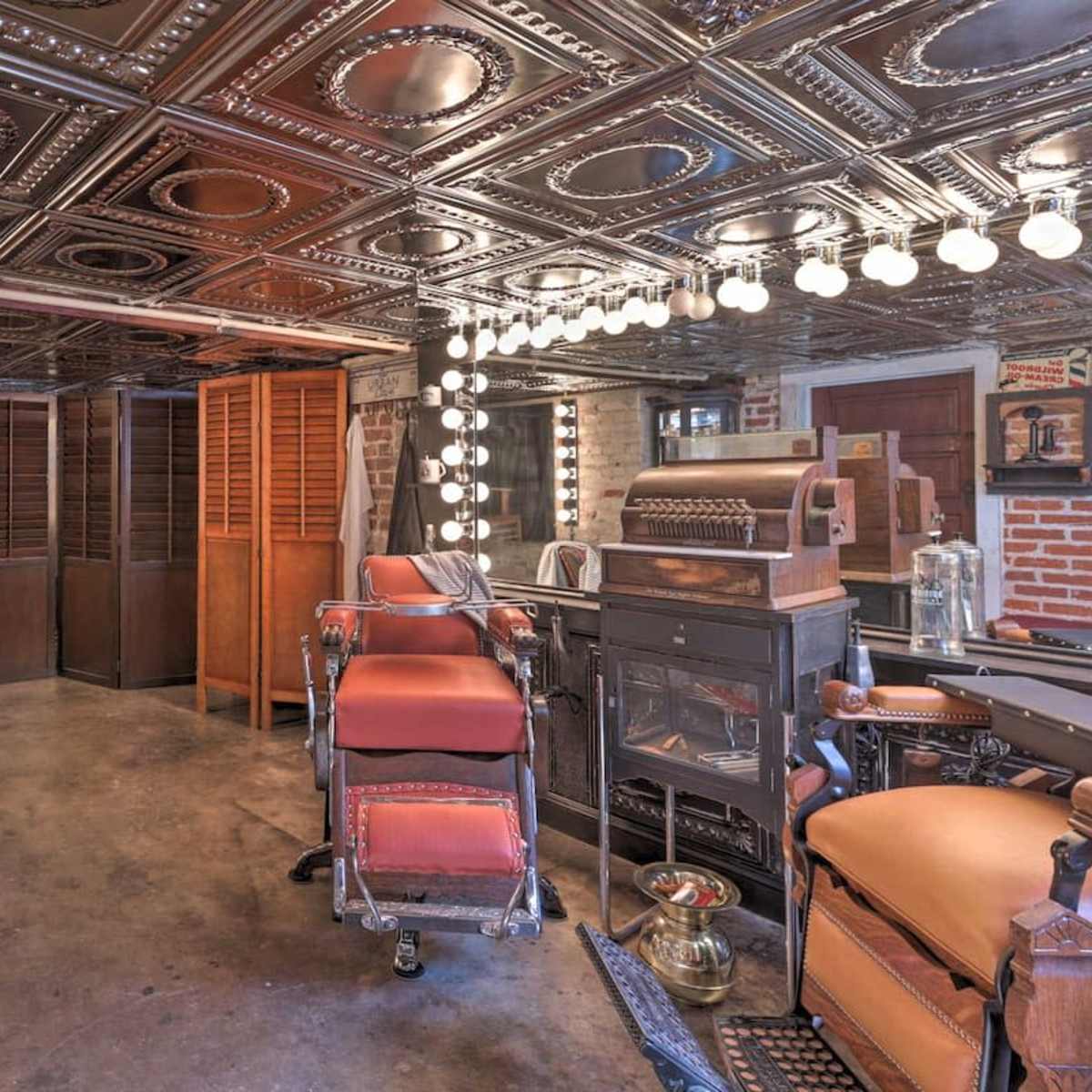 A vintage barber shop interior with a mirrored ceiling, antique furniture, and display cases.