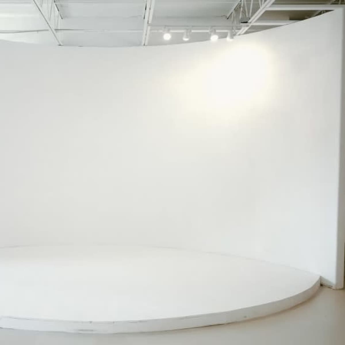 A large, curved white backdrop in a well-lit studio space.