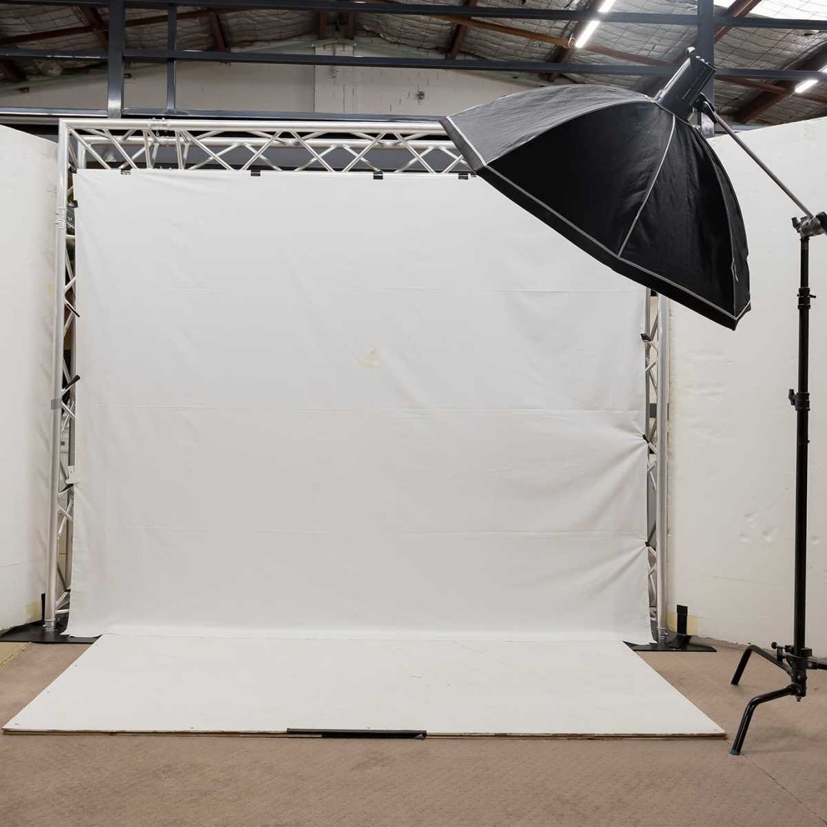 A photography studio setup with a white backdrop and a large softbox light positioned at an angle.