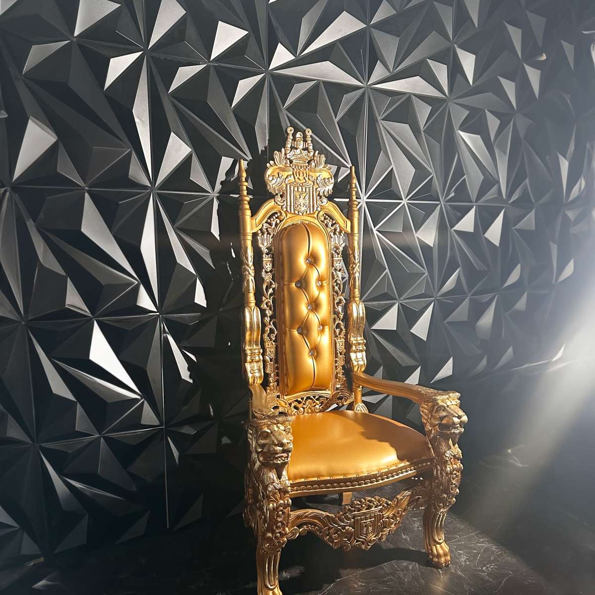 A gilded, ornate throne with lion motifs sits against a textured black wall featuring a geometric design.
