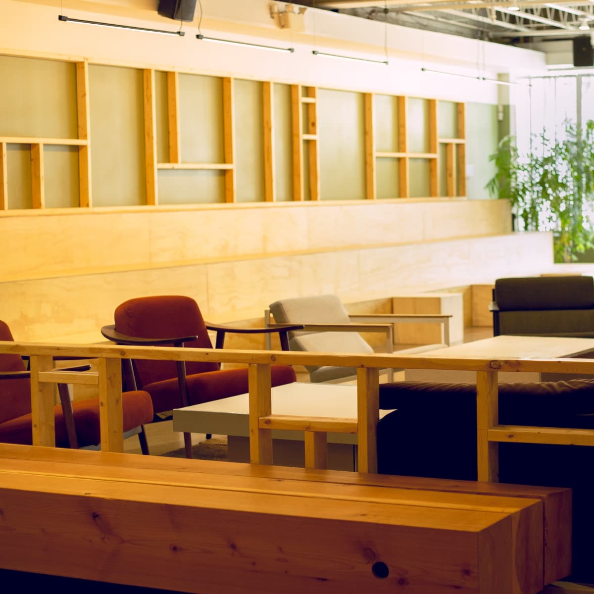 A modern, open lounge area featuring a wooden partition, sofas, chairs, and a coffee table on a polished floor.