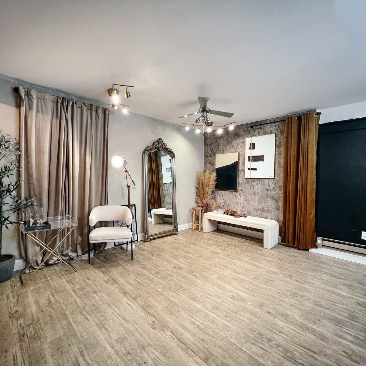 A neatly arranged interior space featuring a large mirror, a modern bench, a decorative plant, and wall art, with a mix of textured walls and soft lighting.