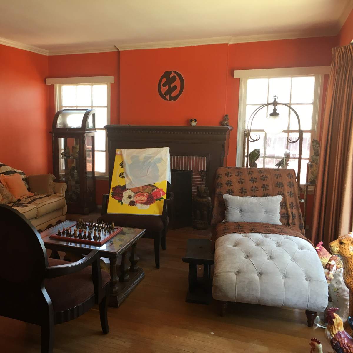 The room features a chess set on a table, a chaise lounge, and two sofas against orange-colored walls.