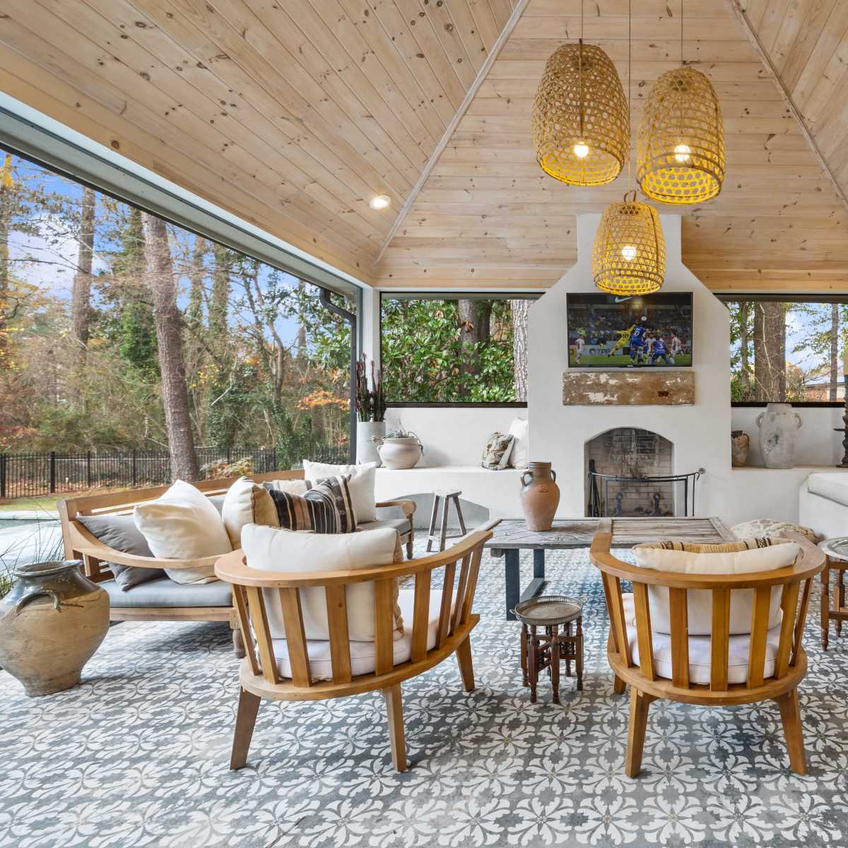 A cozy interior space with a high wooden ceiling, a fireplace, and a seating area furnished with wooden chairs and cushions.