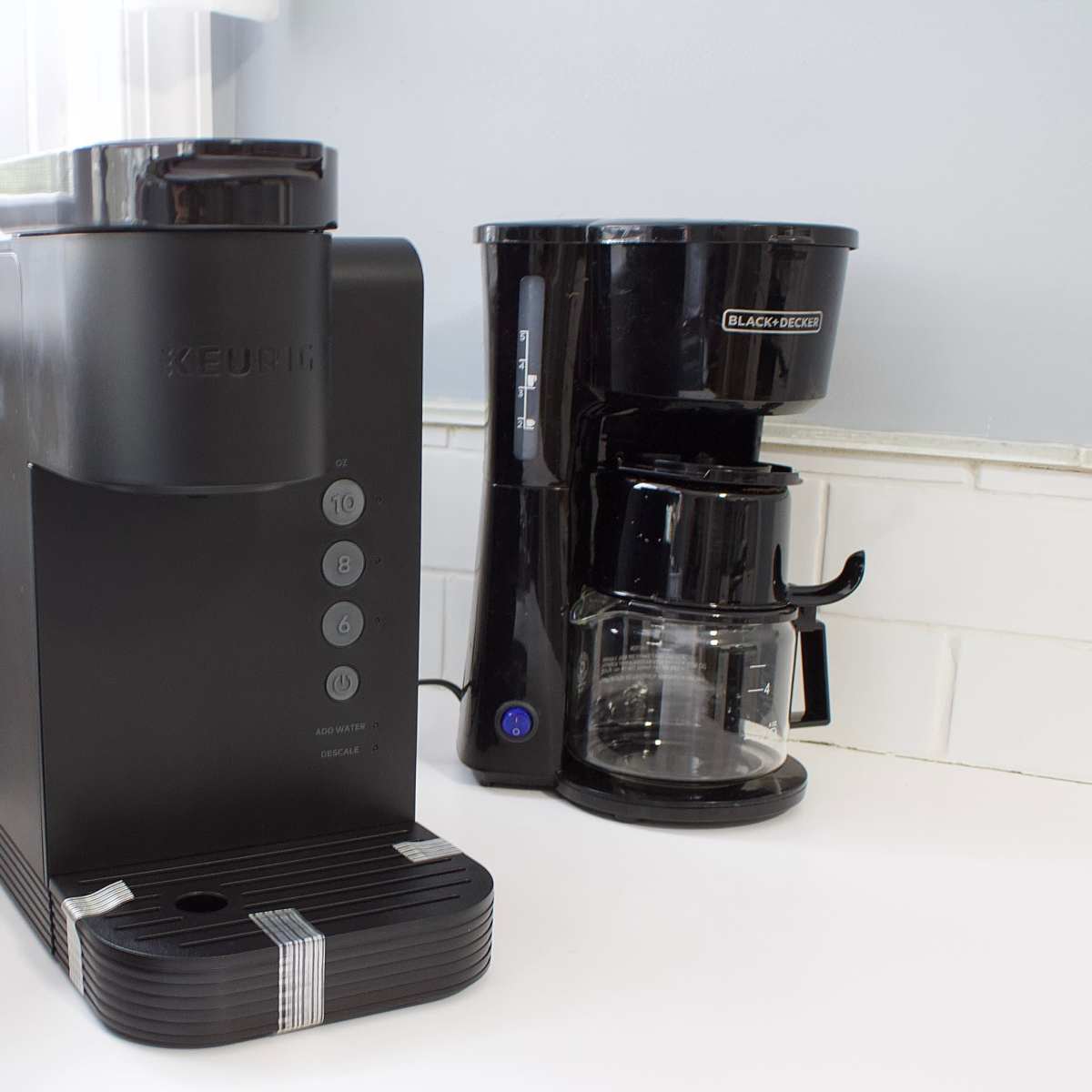 A Keurig coffee maker is placed next to a Black+Decker drip coffee maker on a kitchen countertop.