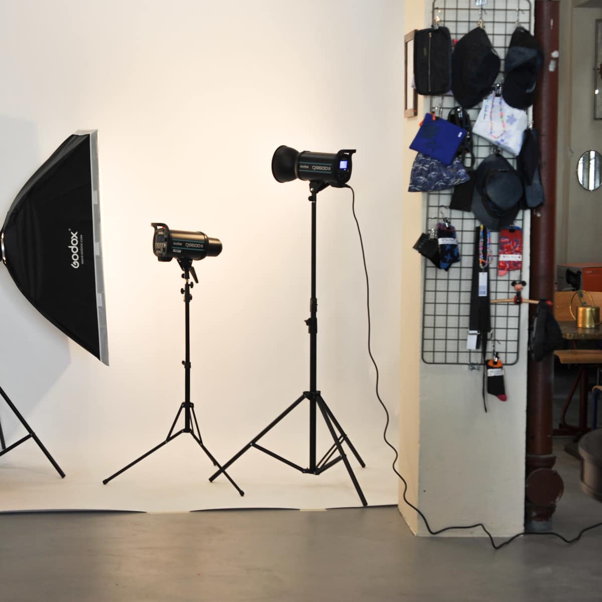 A photography setup featuring three studio lights and a large softbox positioned against a white backdrop in a room.