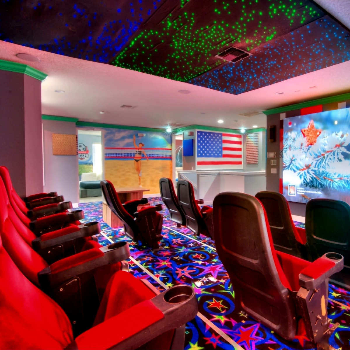 A home theater with red reclining chairs, a large projection screen displaying a winter scene, and colorful star-patterned carpet.