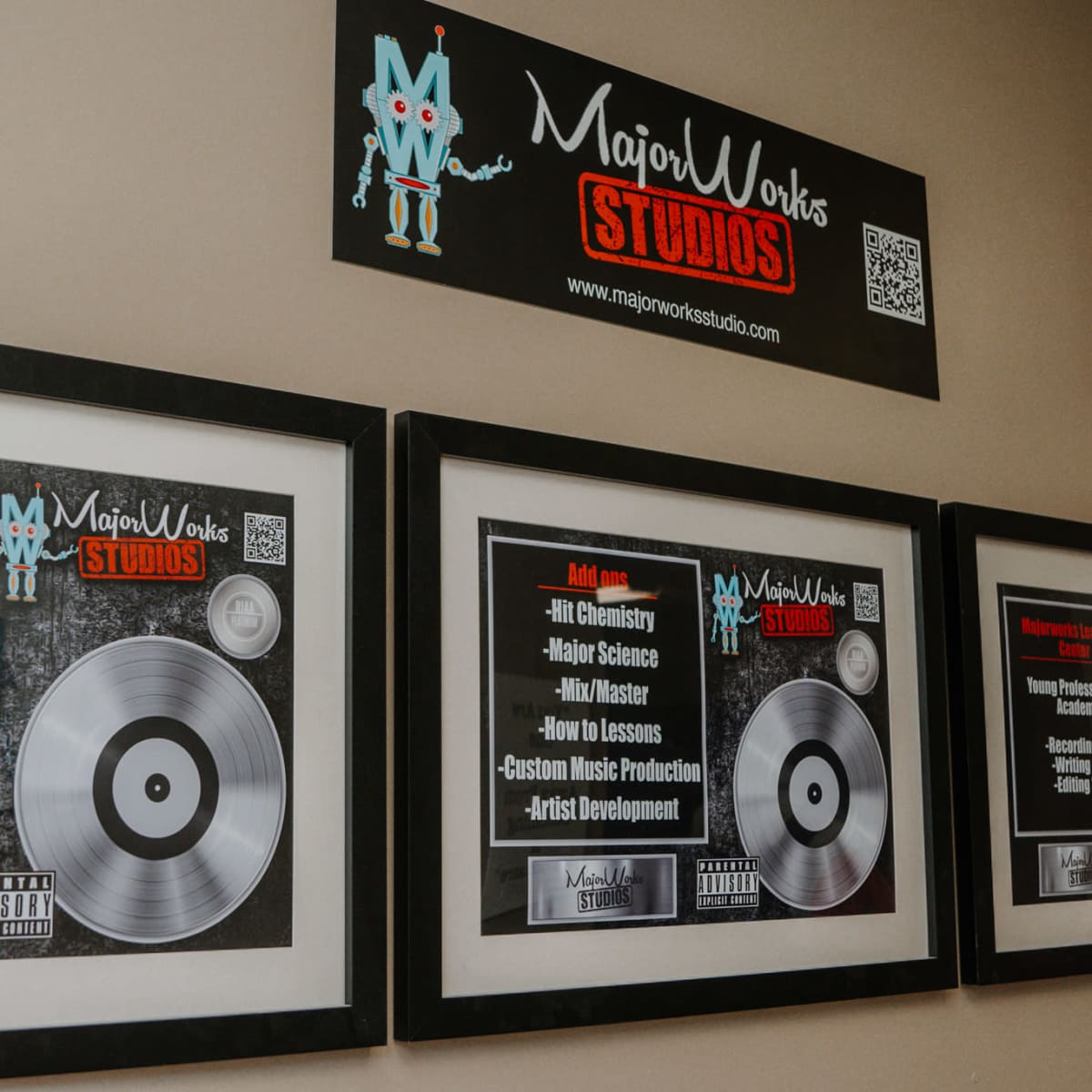 A wall with framed posters of Major Works Studios, featuring various studio names and a vinyl record design.