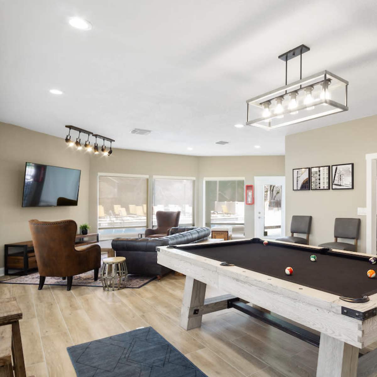 A spacious living area featuring a pool table, a sectional sofa, a television, and a dining area in an open floor plan.