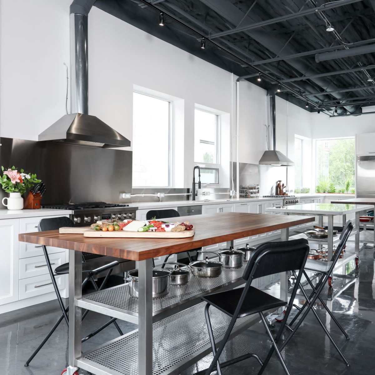 A modern kitchen with stainless steel appliances, a large wooden island, and sleek cabinetry.