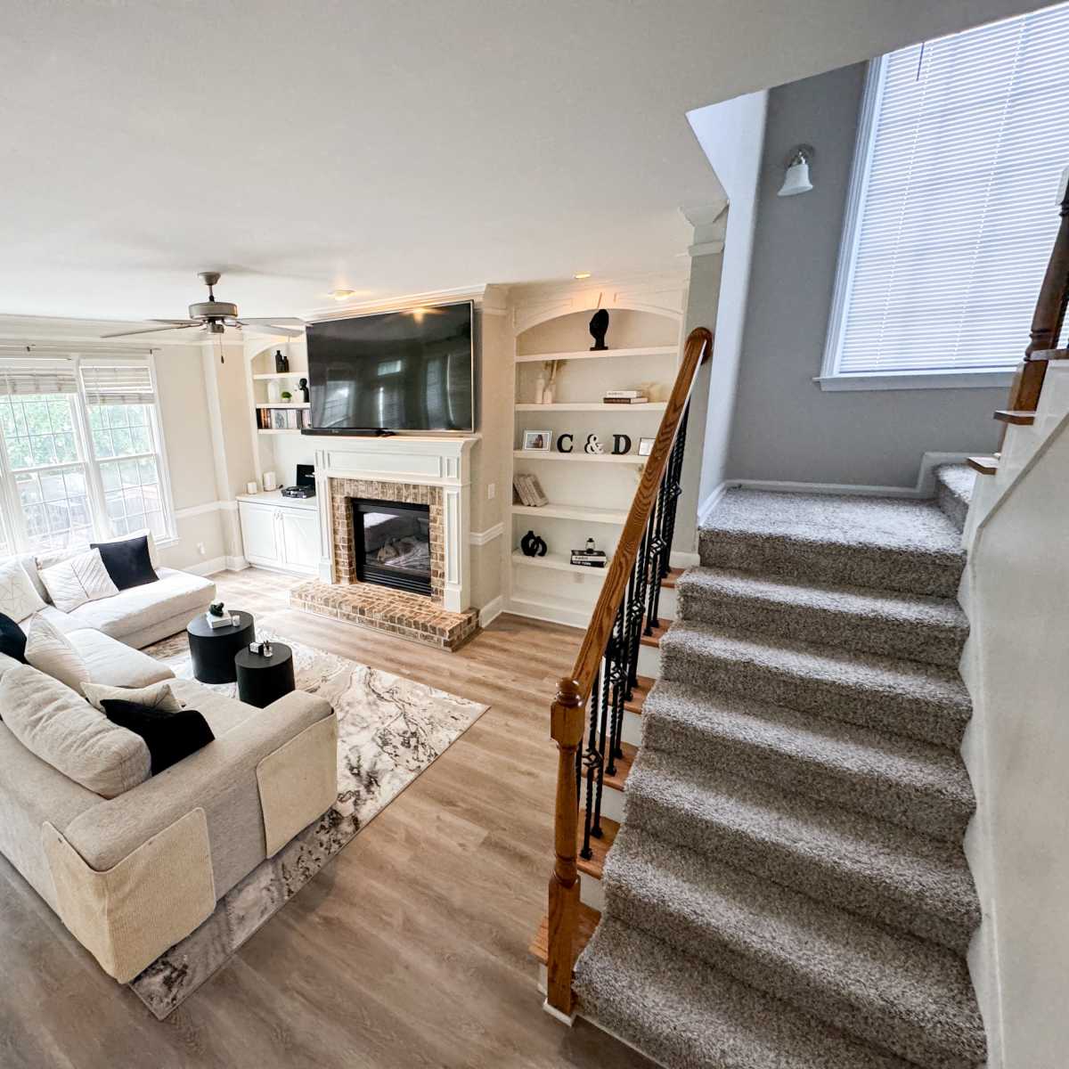A spacious living room with a large sectional sofa, a fireplace, and a staircase leading to another level.